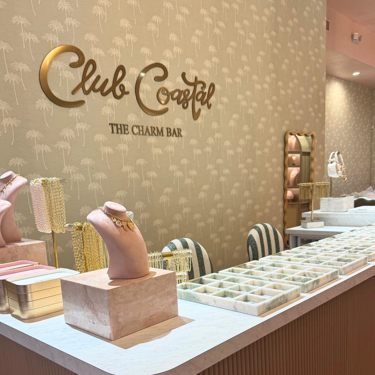 The charm bar inside Club Coastal Charleston with the Club Coastal sign and marble charm trays