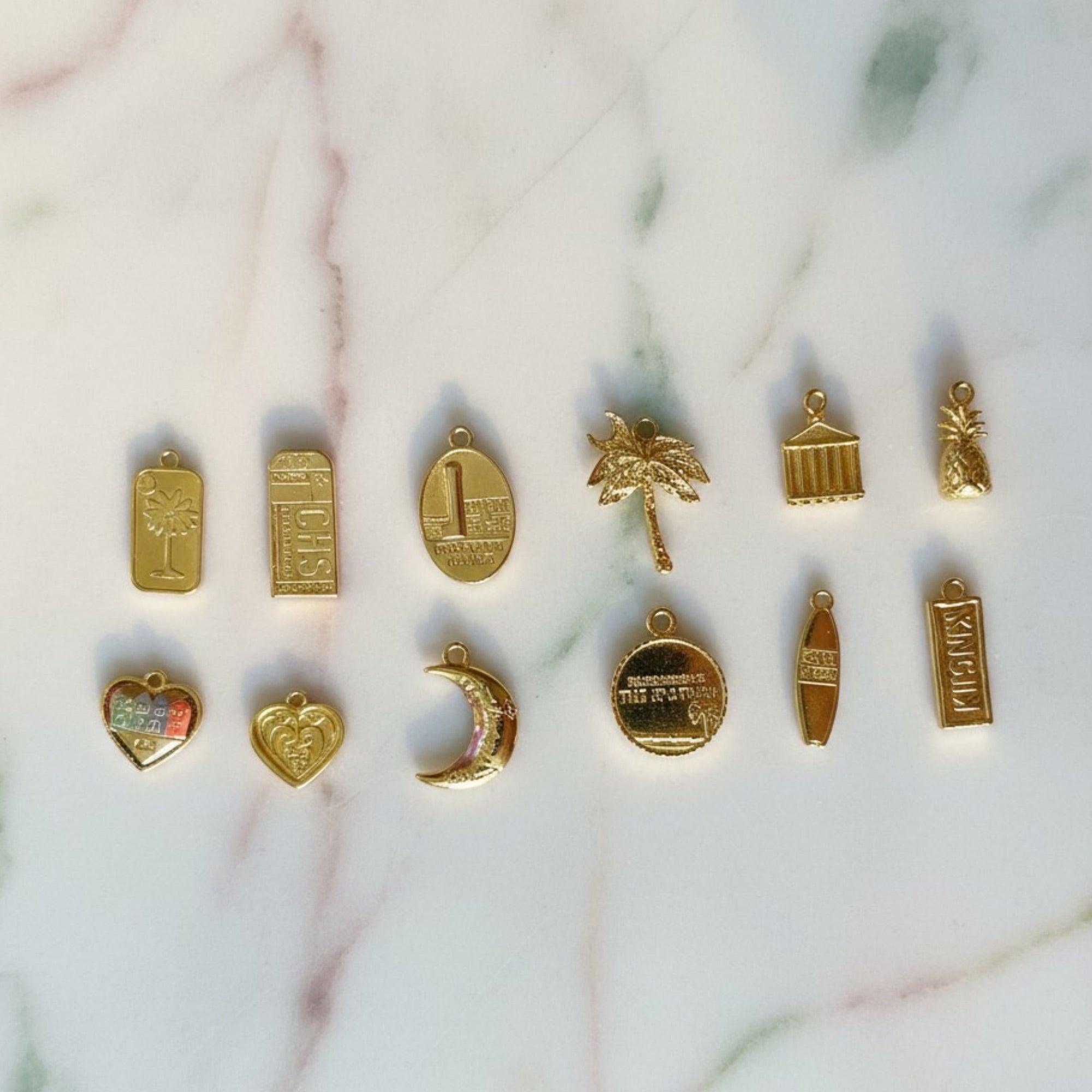 Gold Charleston-only charms laid out on marble