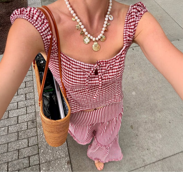 Customer in a red gingham dress wearing a pearl and shell charm necklace