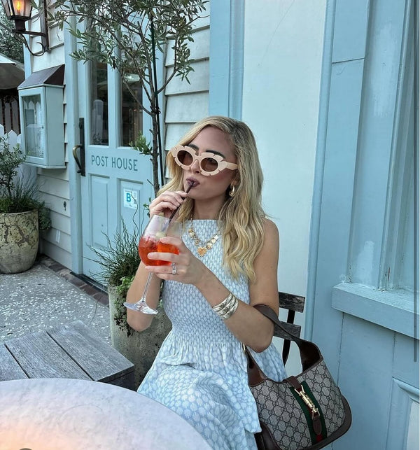 Customer in a blue dress at a cafe wearing layered gold charm necklaces
